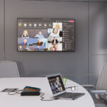 FSR Cable Pilot Retractor on a table within a meeting room set up with cable attached to a laptop and meeting shown on screen on the wall .