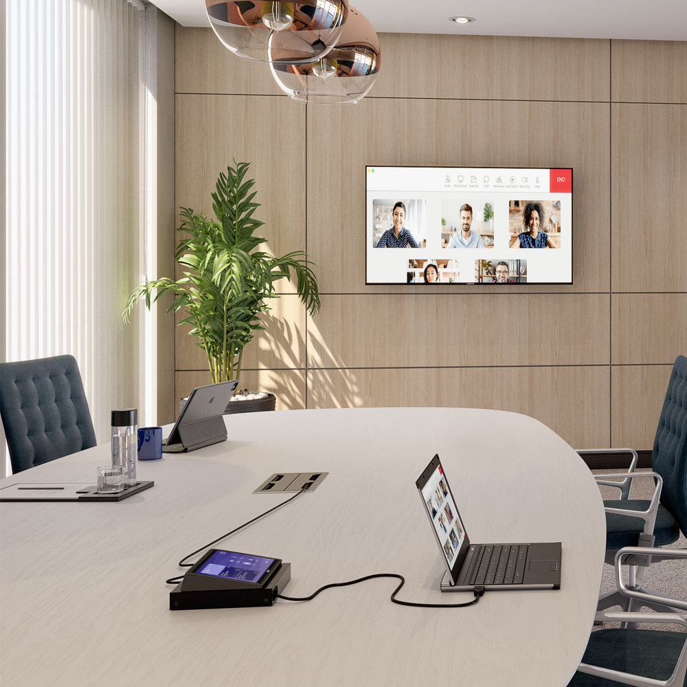 FSR Cable Pilot Retractor on a table within a meeting room set up with cable attached to a laptop and meeting shown on screen on the wall .